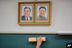 A student cleans the blackboard under the portraits of the late North Korean leaders Kim Il Sung and Kim Jong Il hanging on the classroom wall at a Tokyo Korean high school in Tokyo, Sept. 26, 2017.