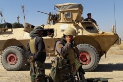 FILE - Afghan security forces stand near an armored vehicle during fighting between Afghan security forces and Taliban fighters in the Busharan area on the outskirts of Lashkar Gah, the capital of Helmand province, May 5, 2021.