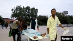 Wafanyakazi wa afya na raia wakiwabeba watu waliojeruhiwa wakiwasili hospitali ya Madina baada ya mlipuko katika hotel ya Elite katika fukwe ya Lido mjini Mogadishu, Somalia, Agosti 16, 2020. 