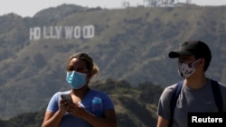 People wearing face masks walk past the Hollywood sign in the distance, after a partial reopening of Los Angeles hiking trails during the outbreak of the coronavirus disease (COVID-19) at Griffith Park in Los Angeles, California, U.S., May 9, 2020. REUTER