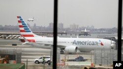 FILE - In a March 13, 2019 file photo, an American Airlines Boeing 737 MAX 8 sits at a boarding gate at LaGuardia Airport in New York. American Airlines said on April 7, 2019 it is extending by over a month its cancellations of about 90 daily flights