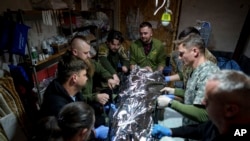 Médicos militares ucranianos colocan a un compañero herido en una camilla en un hospital de campaña en dirección a Avdiivka, en la región de Donetsk, Ucrania, el viernes 10 de mayo de 2024.