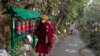 Seorang biksu Buddha Tibet di pengasingan memutar roda doa di jalan yang ditandai dengan lingkaran bagi para pemilih yang antre untuk memberikan suara, guna memastikan jarak sosial, selama pemilu di Dharamsala, India, Minggu (3/1). 