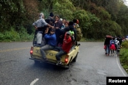Migrants from Honduras, part of a new caravan from Central America trying to reach the United States, walk along a road as others hitch a ride in a truck, in Esquipulas, Guatemala, Jan. 16, 2019.