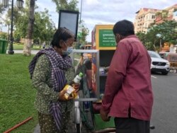 ​អ្នកស្រី នួន ឃាង ពលរដ្ឋដែល​មាន​ស្រុក​កំណើត​នៅ​ខេត្ត​ព្រៃ​វែង កំពុងទួលយក​មី និងទឹក​ពី​ធុង​សហគមន៍​ចល័ត​នៅ​ខាង​វត្ត​បុទុម​ រាជធានី​ភ្នំពេញ នៅ​ថ្ងៃទី​១៦ ខែ​វិច្ឆិកា ឆ្នាំ​២០២១។ (កាន់ វិច្ឆិកា/វីអូអេ)