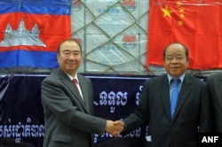 Chinese Ambassador to Cambodia Pan Guang Xue, left, shakes hands with Cambodian first vice president of the National Committee for Disaster Management Nhim Vanda at Phnom Penh international airport, Oct. 15, 2011.