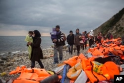 Refugees and migrants walk along a beach after crossing a part of the Aegean on a dinghy, from Turkey to the Greek island of Lesbos, Dec. 12, 2015.