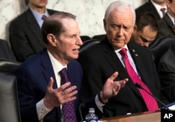 Sen. Ron Wyden, D-Ore., left, the top Democrat on the Senate Finance Committee, criticizes the Republican tax reform plan while Chairman Orrin Hatch, R-Utah, listens to his opening statement as the panel begins work overhauling the nation's tax code, on Capitol Hill in Washington, Nov. 13, 2017.