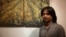 Nov Cheanick, a Battambang-based painter, is pictured in front of his own painting at TINI café in Phnom Penh, Cambodia, September 27, 2017. (Tum Malis/VOA Khmer)
