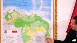 ARCHIVO - El presidente de la Comisión Especial para la Defensa de Esequibo, Hermann Escarra, junto a un nuevo mapa de Venezuela que incluye la región de Esequibo, en Caracas, Venezuela, el 8 de diciembre de 2023.