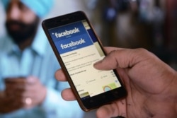 FILE - An man looks at a Facebook app on his smartphone in Amritsar, India, March 22, 2018.