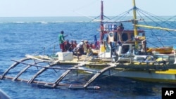 FILE - In this photo provided by Renato Etac, Chinese Coast Guard members, wearing black caps and orange life vests, approach Filipino fishermen as they confront them off Scarborough Shoal in the South China Sea.