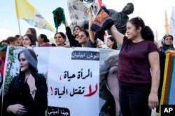 Kurdish women activists hold head coverings and a picture of Iranian woman Mahsa Amini, with Arabic that reads, "The woman is life, don't kill the life," during a protest against her death in Iran, at Martyrs' Square in downtown Beirut, September 21, 2022. (AP Photo/Bilal Hussein, File)