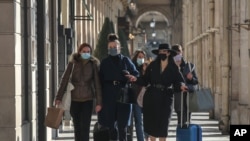 Mujeres que usan mascarillas faciales como precaución contra el coronavirus caminan en la rue Rivoli en París, el viernes, 6 de noviembre de 2020.