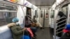 Des personnes portant des masques pour contrer l'épidémie de COVID-19, sont dans une cabine de train à la station de métro Times Square à New York, États-Unis, le 17 avril 2020. REUTERS / Jeenah Moon