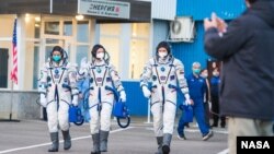 អវកាសយានិក​អង្គការ​ណាសារបស់​សហរដ្ឋអាមេរិក​អ្នកស្រី Kate Rubins (ឆ្វេង) អវកាសយានិក​របស់​រុស្ស៊ីលោក Sergey Ryzhikov (កណ្ដាល) និង​លោក Sergey Kud-Sverchkov (ស្ដាំ) ដើរ​ចេញ​ពី​អគារ ២៥៤ ទៅ​កាន់​យាន​អវកាស​ Soyuz MS-17 ក្នុង​ដំណើរ​ទៅ​កាន់​ស្ថានីយ៍​អវកាស​ ថ្ងៃទី១៤ ខែតុលា ឆ្នាំ២០២០។ 