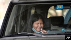 FILE - Ashley Ruiz gives herself a COVID-19 nasal swab test while sitting in a car at a drive-up CVS pharmacy in Dallas, Sept. 18, 2020.