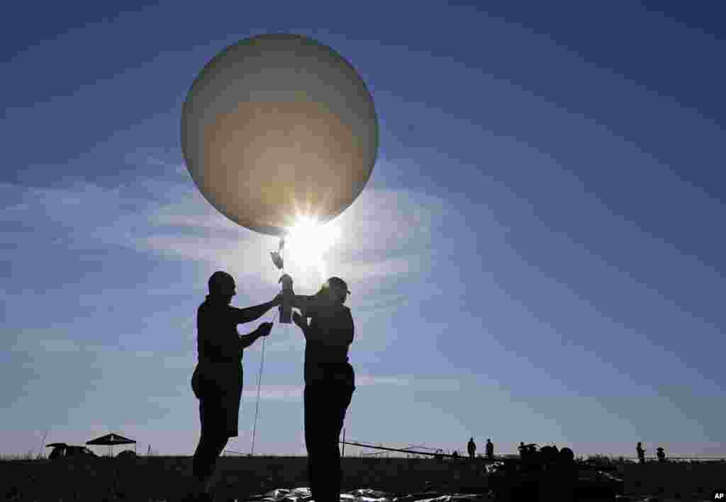 Mike Newchurch, left, professor of atmospheric chemistry at the University of Alabama in Huntsville, and graduate student Paula Tucker prepare to launch a weather balloon to do research during the solar eclipse, on the Orchard Dale historical farm near Hopkinsville, Kentucky, Aug. 21, 2017.