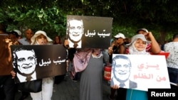 Supporters of presidential candidate Nabil Karoui, hold his pictures as they take part in a rally asking for his release from prison, in front of the courthouse in Tunis, Tunisia, Sept. 3, 2019. 
