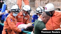 A rescue team carries a wounded worker at a collapsed building in Sihanoukville, Cambodia, June 22, 2019.
