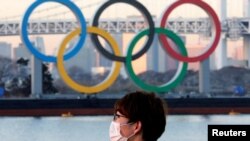 Un japonés usa una mascarilla protectora en plena pandemia frente a unos enormes anillos olímpicos en Tokio. [Foto de archivo]
