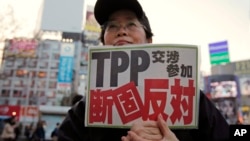 FILE - A protester holds a sign reading "We oppose Japan to join the TPP negotiation talks" during a rally against the Trans-Pacific Partnership in Tokyo. 