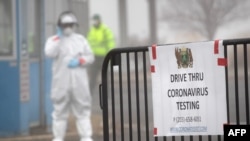 FILE - A sign sits on a barrier at a coronavirus (COVID-19) drive thru testing location operated by Murphy Medical Associates at Cummings Park in Stamford, Connecticut, March 20, 2020.