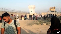 Baadhi ya wachezaji wa mpira wa miguu wa timu ya wasichana ya taifa ya Afghanistan na familia zao wakisubiri nje ya uwanja wa ndege wa Kabul Jumapili, Agosti 29, 2021. Juhudi za kuwasaidia kuondoka nchini ziligonga ukuta baada ya mlipuko wa bomu kutokea. (AP Photo)