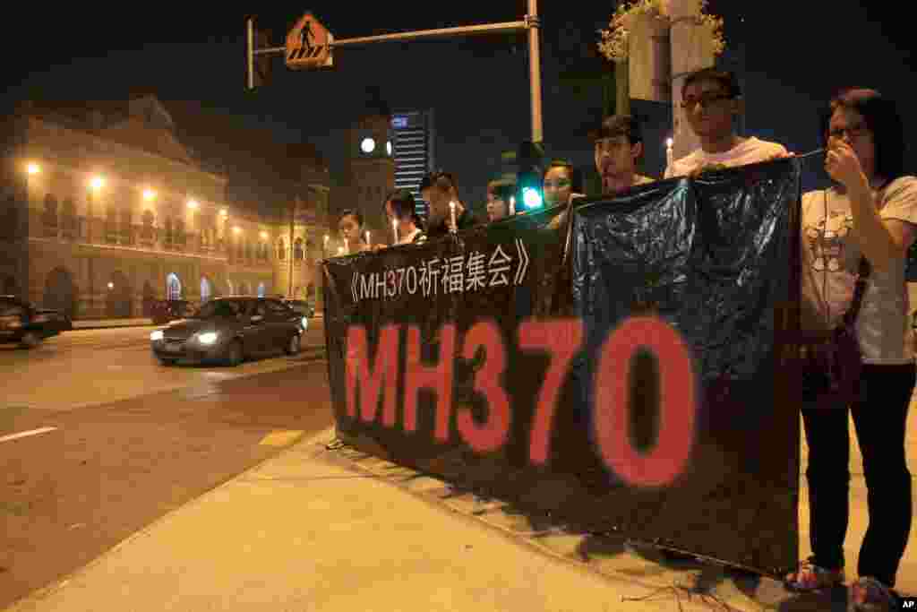 People hold a banner and candles during a candlelight vigil for passengers aboard a missing Malaysia Airlines plane in Kuala Lumpur, Malaysia, March 10, 2014.&nbsp;