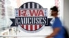 ARCHIVO - Un peatón pasa junto a un cartel de los Caucus de Iowa en una pasarela elevada en el centro de Des Moines, Iowa, el 4 de febrero de 2020.