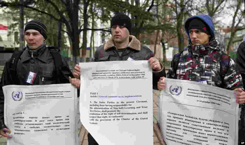 Pro-Russian demonstrators hold large copies of United Nations documents on the right to self-determination outside the regional parliament building in Simferopol, Crimea, Ukraine, March 16, 2014. 
