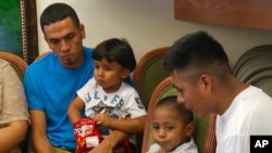 En esta imagen tomada de video, Javier Garrido Martínez (izquierda) y Alan García (derecha), dan una conferencia de prensa en Nueva York luego de haber sido reunidos con sus hijos. Julio, 2018.