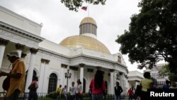 Personas pasan frente al edificio de la Asamblea Nacional durante una sesión parlamentaria en Caracas, Venezuela, el 14 de diciembre de 2016.