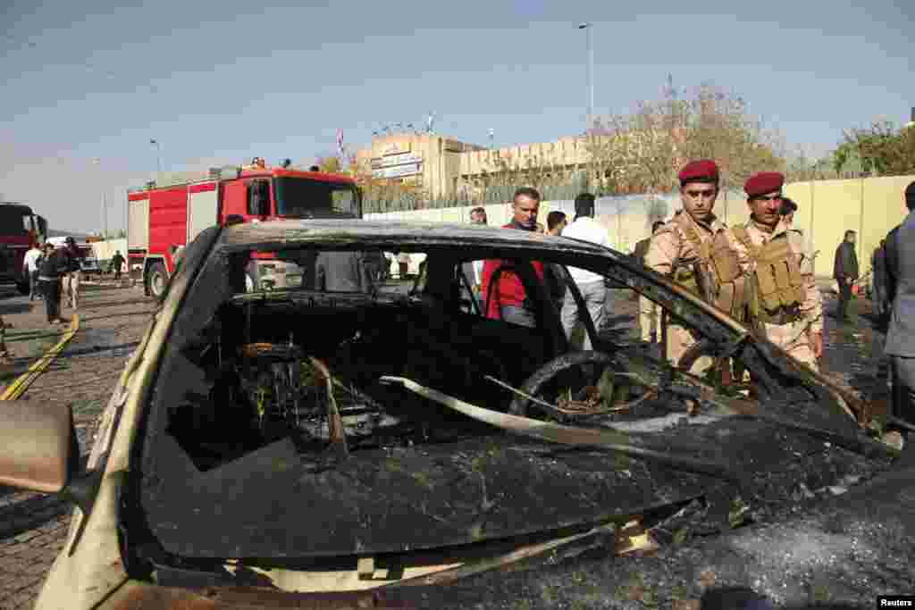Kurdish security forces inspect the car used in the attack in Irbil, Nov. 19, 2014.