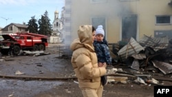 A local resident and her child walks past the railway station destroyed by a Russian missile attack in Kostyantynivka, Donetsk region, on Feb. 25, 2024, amid Russia's invasion of Ukraine.