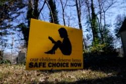 Sebuah banner bertuliskan: "Anak-anak kita pantas mendapatkan pilihan (pendidikan) yang aman saat ini" di Decatur, Georgia, AS.