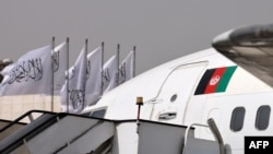 Sobiq hukumat bayrog'i aks etgan samolyot Tolibon bayroqlari o'rnatilgan aeroportda. Kobul, 11-sentabr, 2021. 