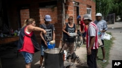 Voluntarios sirven almuerzos calientes en el comedor social "Regalo de Dios" en el barrio Libertador de Buenos Aires, Argentina, el jueves 22 de febrero de 2024.