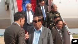 Cambodian Prime Minister Hun Sen, center, talks with an official as Tea Banh Tea Banh, lower right, Deputy Prime Minister and Minister of National Defense, deplanes upon their arrival from a trip to Laos, at the airport, in Phnom Penh, Cambodia, Saturday, Aug. 12, 2017. Cambodian Prime Minister Hun Sen, who threatened Friday to use force over a border crisis with neighboring Laos, has announced less than 24 hours later that he has peacefully resolved it. (AP Photo/Heng Sinith)