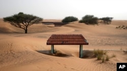 A house's entrance gate is buried under the sand at the Bedouin village of al-Ghuraifabout 100 km, 62 miles, southeast of Sharjah, United Arab Emirates, Sunday, July 9, 2023. (AP Photo/Kamran Jebreili)