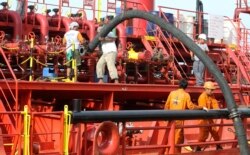 Pekerja memasang pipa untuk memompa minyak sawit mentah (CPO) ke kapal tanker di pelabuhan Belawan di Provinsi Sumatera Utara, 21 Februari 2013. (Foto: REUTERS/Roni Bintang)