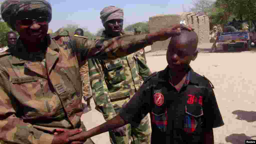 Wani sojan Chadi rike da wani yaro wanda tsohon sojan Boko Haram ne, a garin Ngouboua ran 22 Afrilu, 2015. Yaran sun ce su 'yan kasar Chadi ne wadanda aka tilasta musu shiga kungiyar Boko Haram lokacin da suke karatun allo a Najeriya, amma daga baya sun kubuce suka gudu, suka mika kawunansu ga sojojin Chadi.