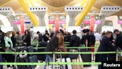 FILE PHOTO: Passengers wait for checking-in before boarding their flights to the U.S. at Madrid's Adolfo Suarez Barajas airport