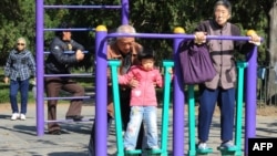 中國第七次人口普查數據顯示，中國人口“低速增長”，趨於老化。圖為北京天壇公園裡的老年人和他們的獨生子女的孫輩在鍛煉身體。 （法新社2011年10月25日資料照）