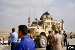 Iraqi Christians on the outskirts of the town of Bartilla watch Iraqi military vehicles advancing. Most Christians have been blocked from visiting their homes with Iraqi military officials saying the area remains unsafe, Bartilla, Iraq, Oct. 31, 2016. (J. Dettmer/VOA)