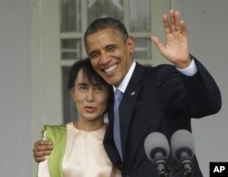 US President Barack Obama (R) waves as he embraces Burmese democracy activist Aung San Suu Kyi after addressing members of the media at Suu Kyi's residence in Rangoon, Burma, November 19, 2012.