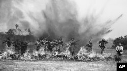 Ranger Troops of the U.S. Army demonstrate charging through a wall of fire as land mines explode behind them during maneuvers at Camp Rucker, Ala., March 5, 1943. (AP Photo)