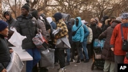 ARCHIVO - Migrantes recogen mantas cerca de un Centro de Asistencia a Migrantes en la Escuela Primaria St. Brigid el martes 5 de diciembre de 2023 en Nueva York.