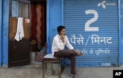 បុរស​ម្នាក់​សន្ទនា​តាម​ទូរស័ព្ទដៃនៅ​មុខហាង​ទំនិញ​បិទទ្វារ។