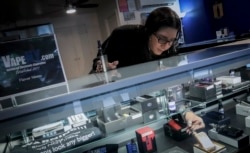 In this Tuesday, Oct. 8, 2019, photo Spike Babaian, owner of several Vape New York stores, works in her East Harlem store in New York.